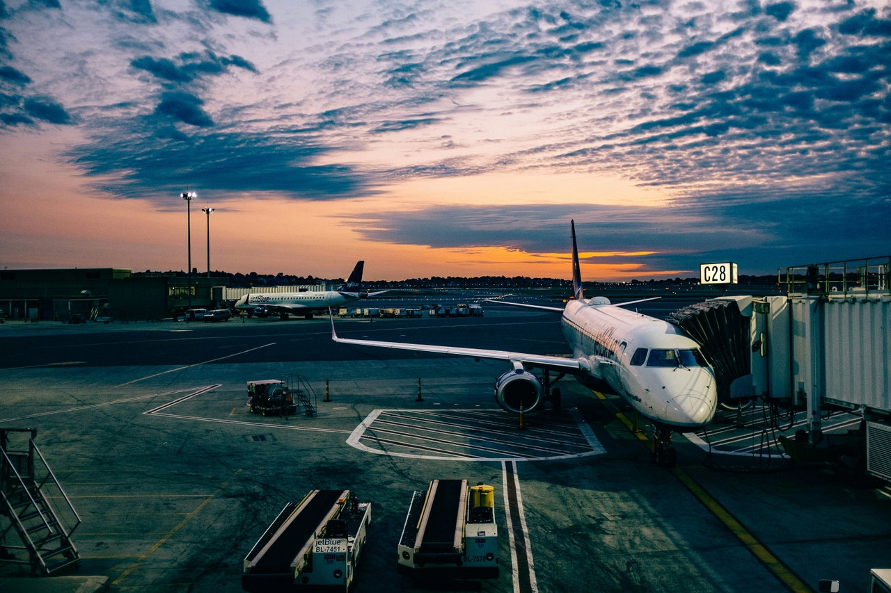 Passenger aircraft at an airport gate at dusk under a dramatic cloudy sky