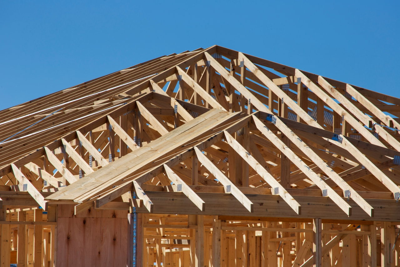 Neuer Dachstuhl aus hellem Holz vor blauem Himmel