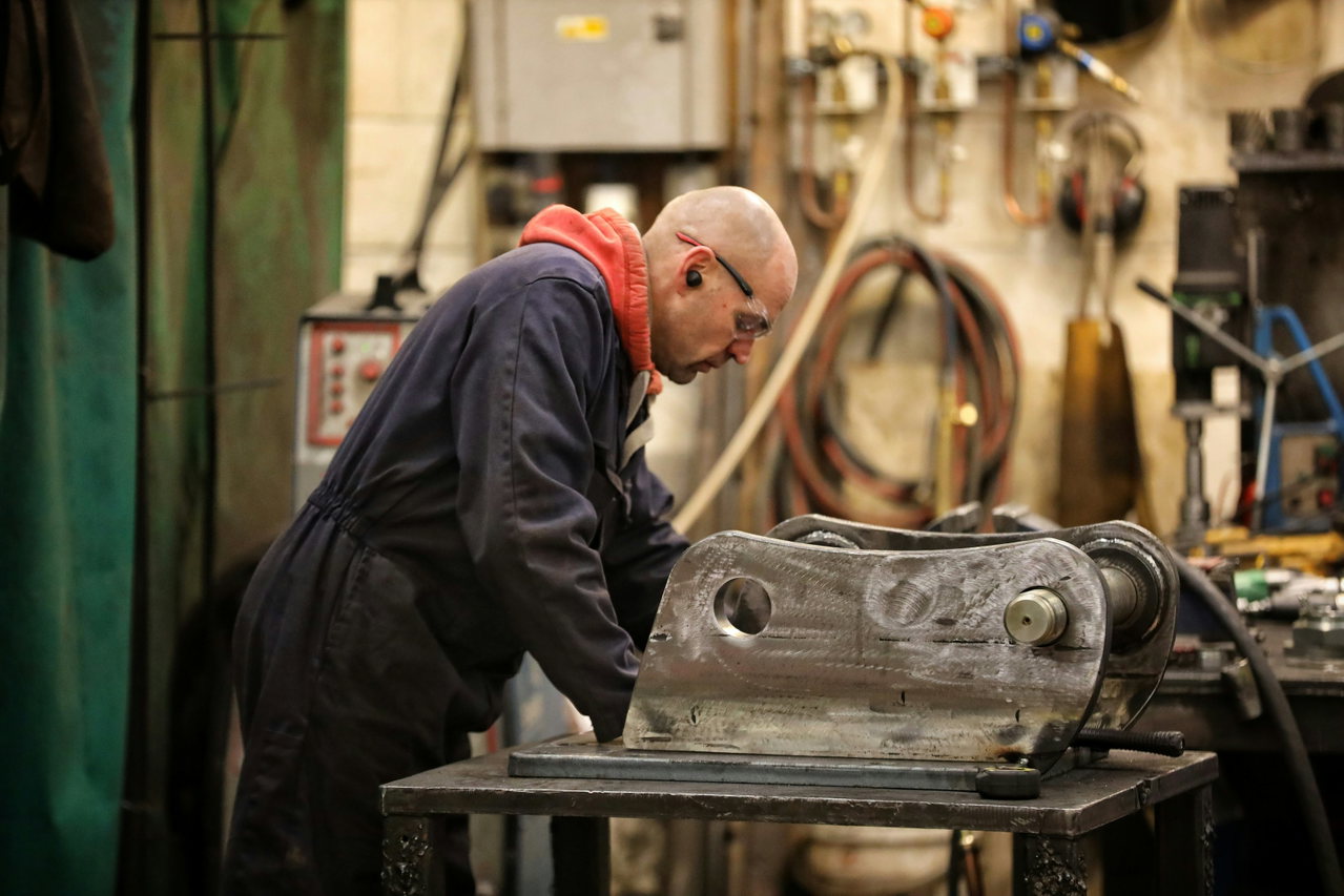 Techniker im Overall arbeitet in einer Werkstatt an einem großen Maschinenbauteil.
