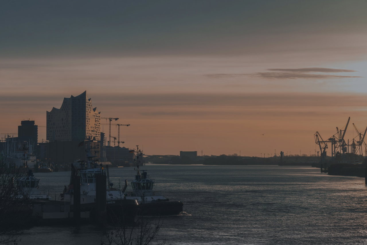 Sonnenaufgang über der Elbe, links die Elbphilharmonie, rechts Hafenkräne