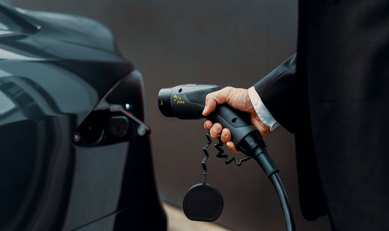 Eine Hand hält den Ladestecker eines Elektroautos