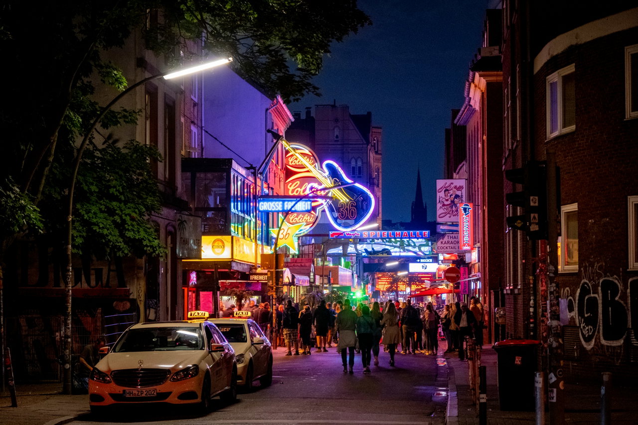 Die Reeperbahn bei Nacht mit Leuchtreklamen und Taxis