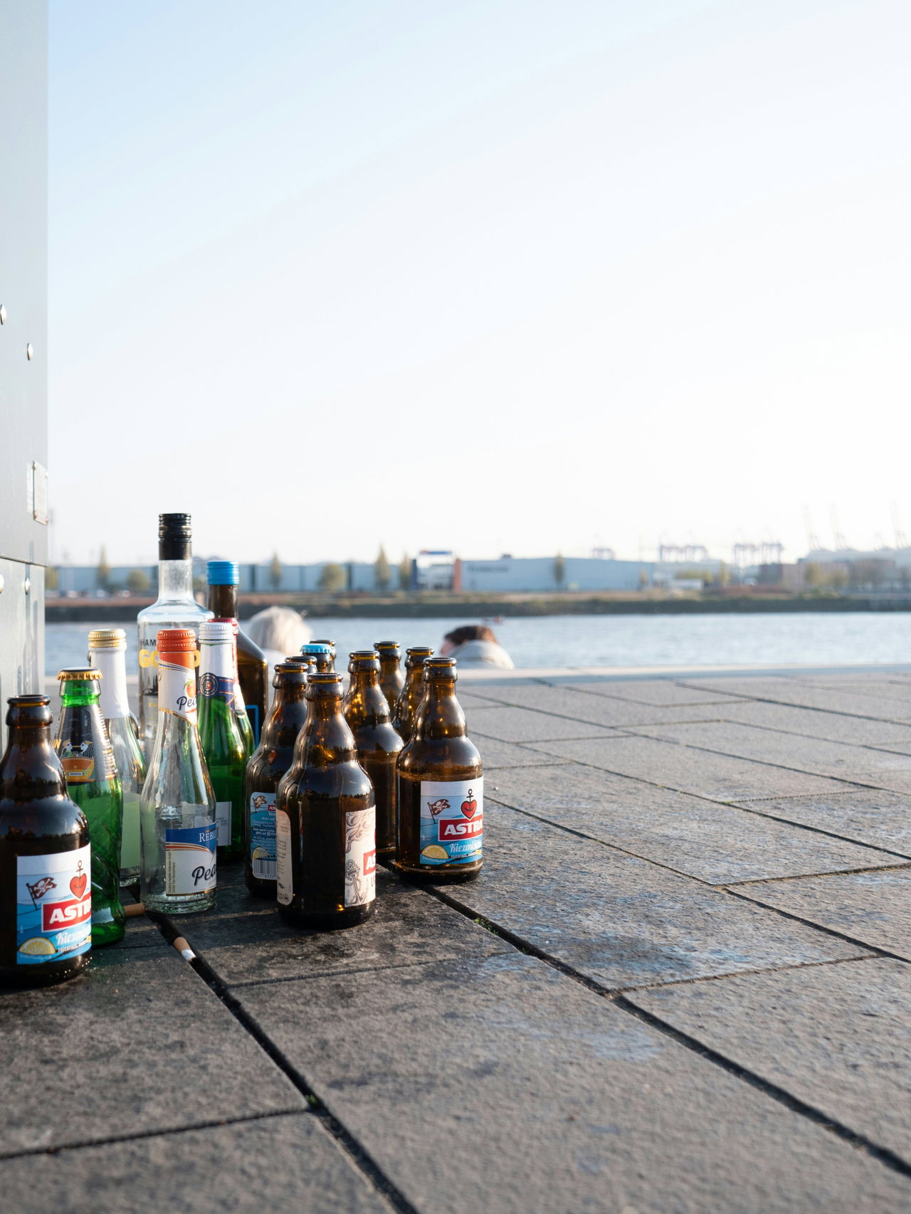 Flaschen auf einer Kaimauer, dahinter die Elbe