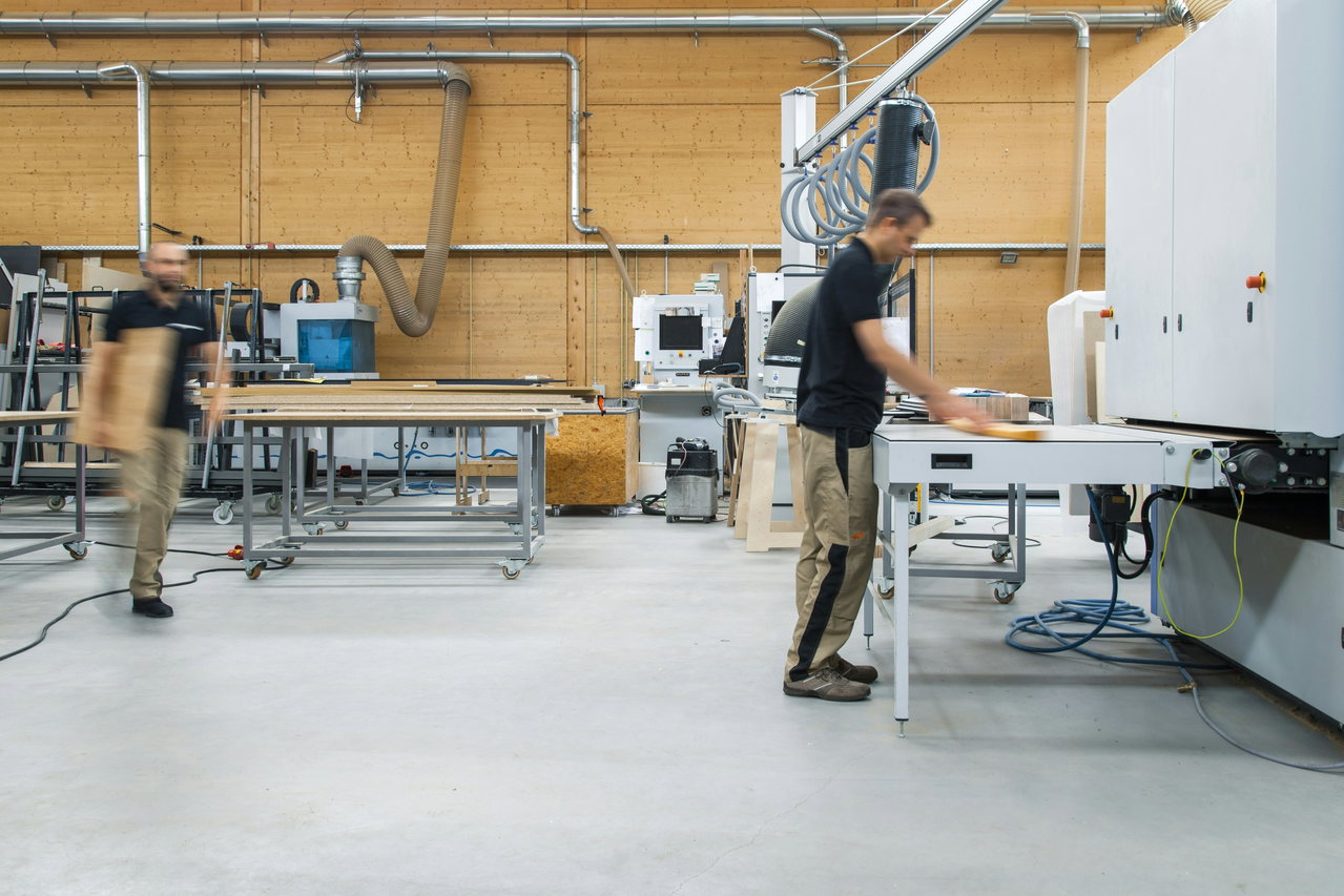 Mitarbeiter arbeiten an einer Maschine in einer hellen Werkhalle