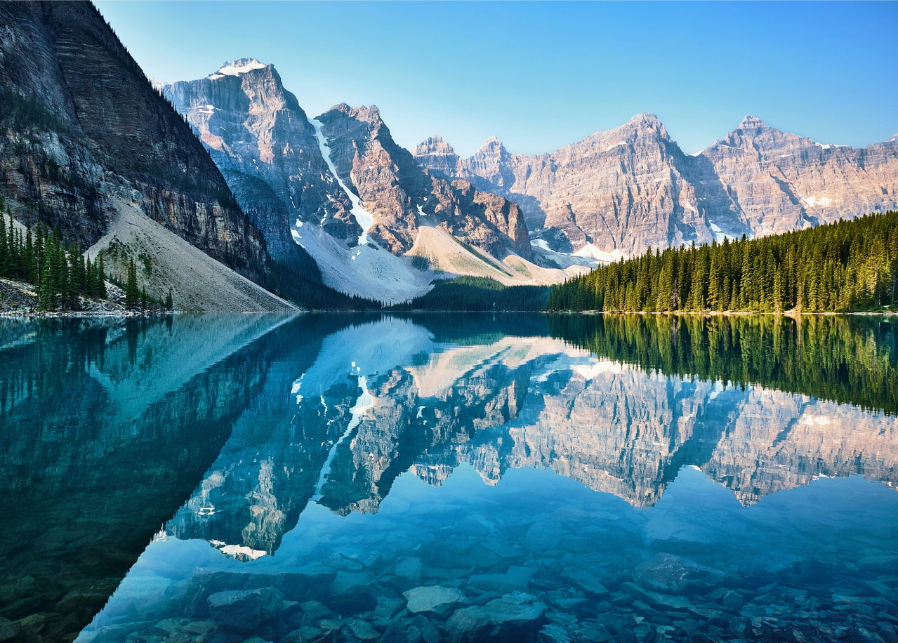 Zackige Berggipfel spiegeln sich in einem klaren Bergsee in den kanadischen Rocky Mountains