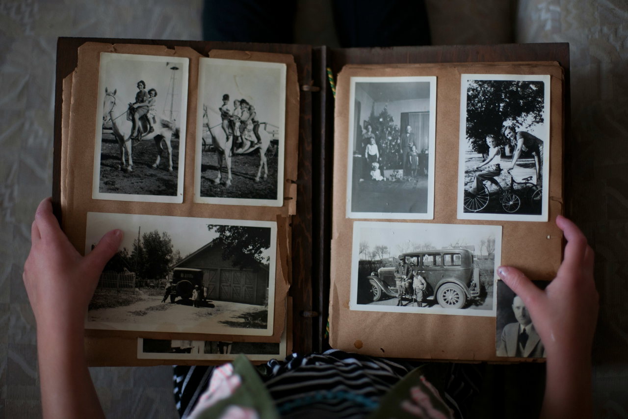 Hände halten ein aufgeschlagenes Fotoalbum mit alten Schwarz-Weiß-Fotos