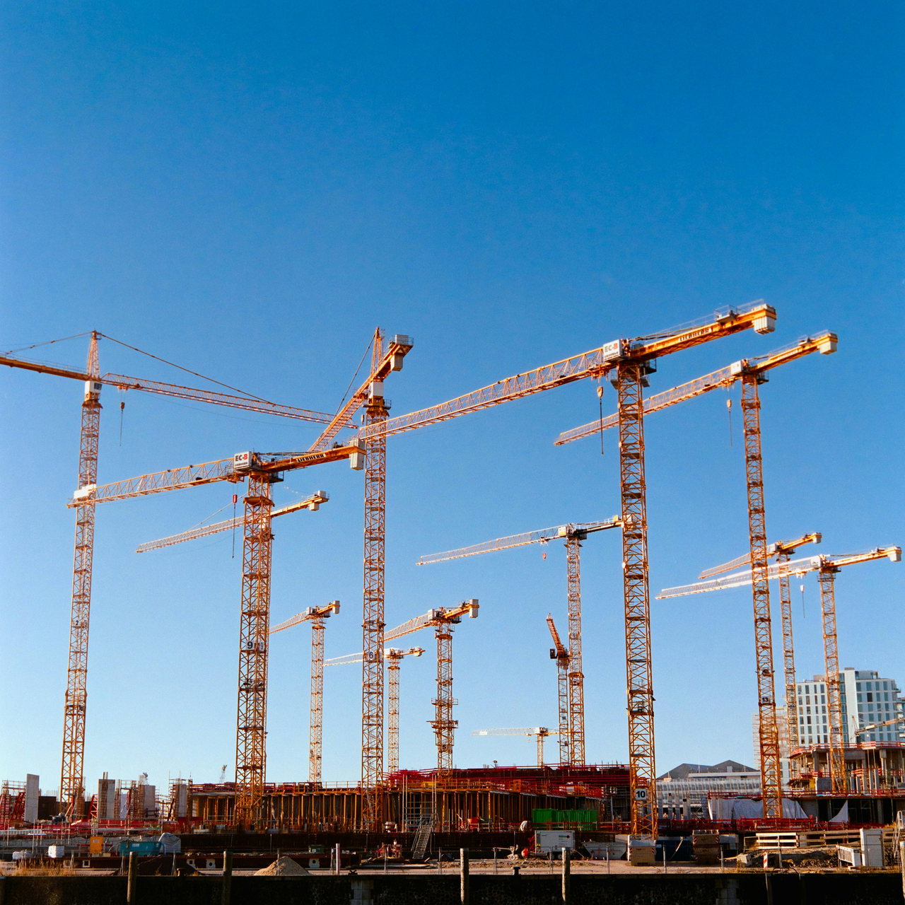 Großbaustelle mit einem Dutzend Turmdrehkränen vor blauem Himmel