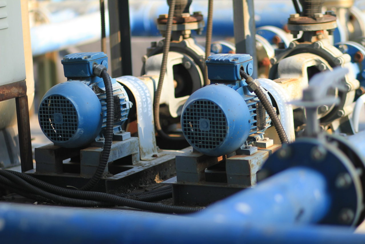 Zwei blaue Elektromotoren treiben in einer Industrieanlage Pumpen an.