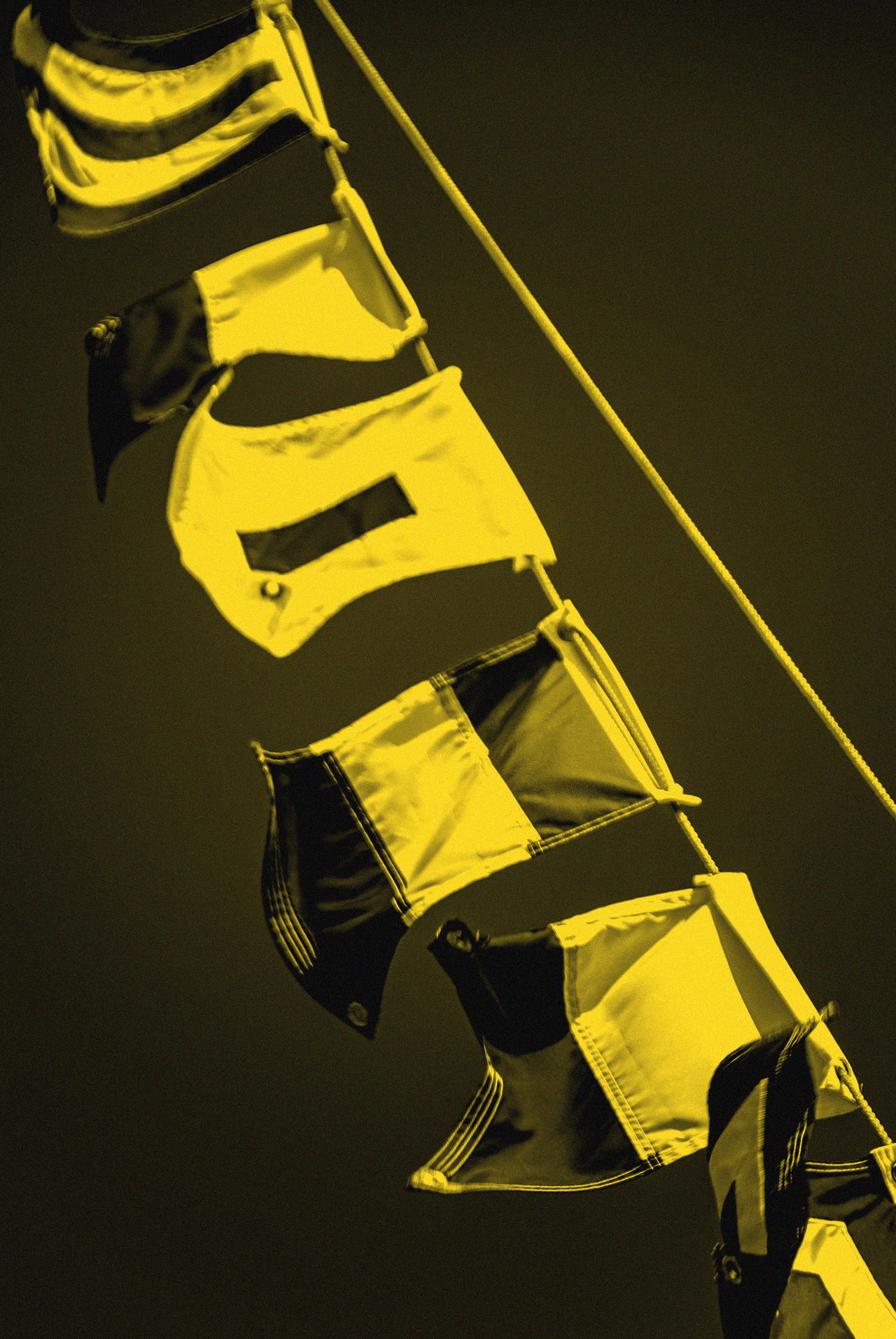 Bunte Signalflaggen flattern an einer Leine vor tiefblauem Himmel (Duplex in Schwarz und Gelb)