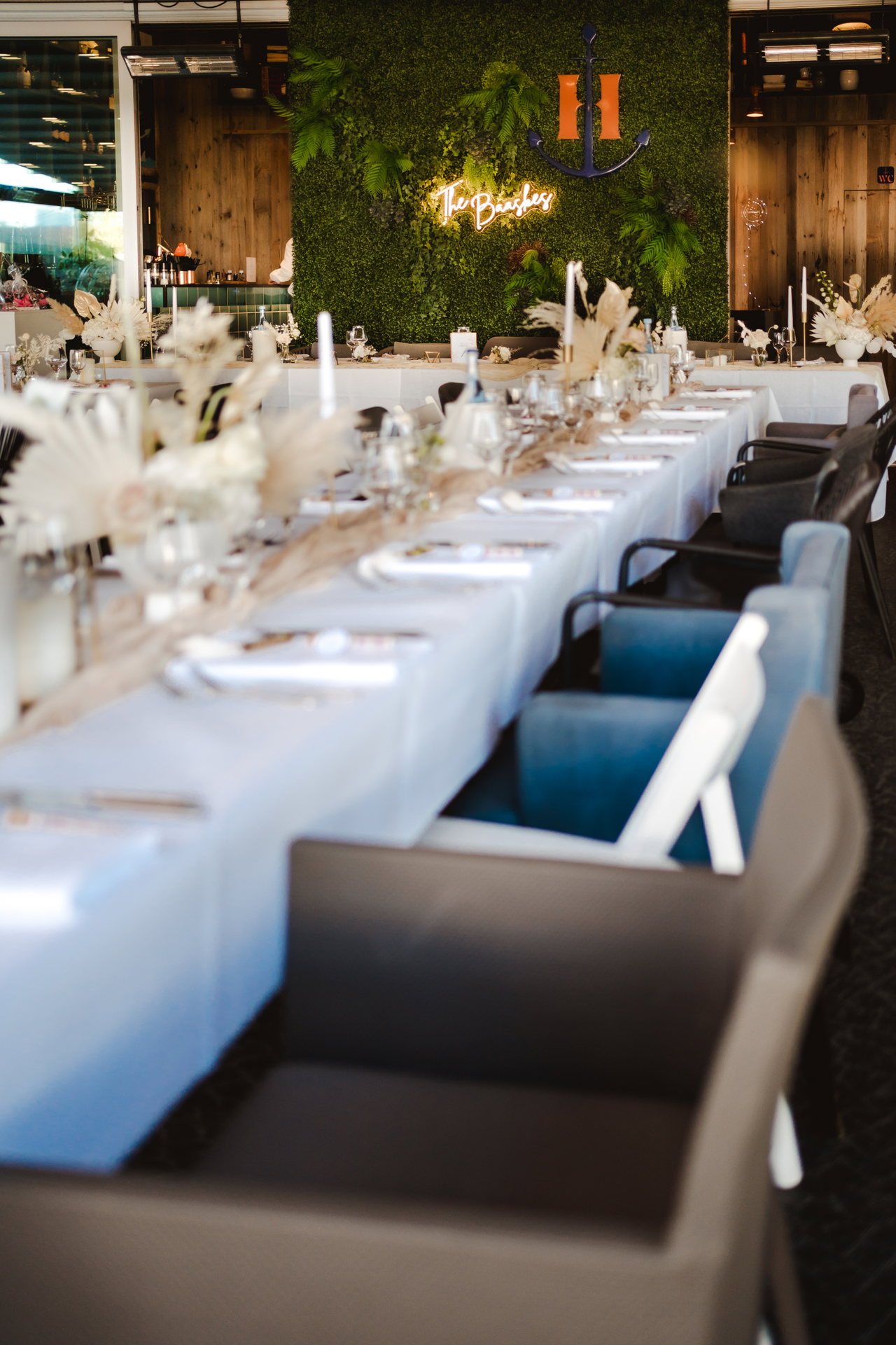 Lange Tafel mit weißen Decken, im Hintergrund das Neonschild
