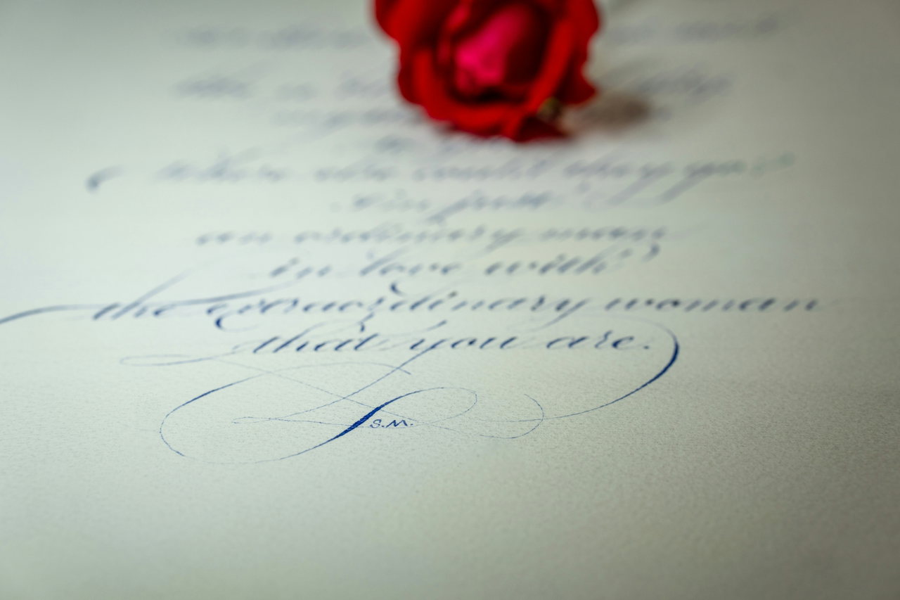 Handgeschriebener Brief in blauer Tinte, oben eine rote Rose