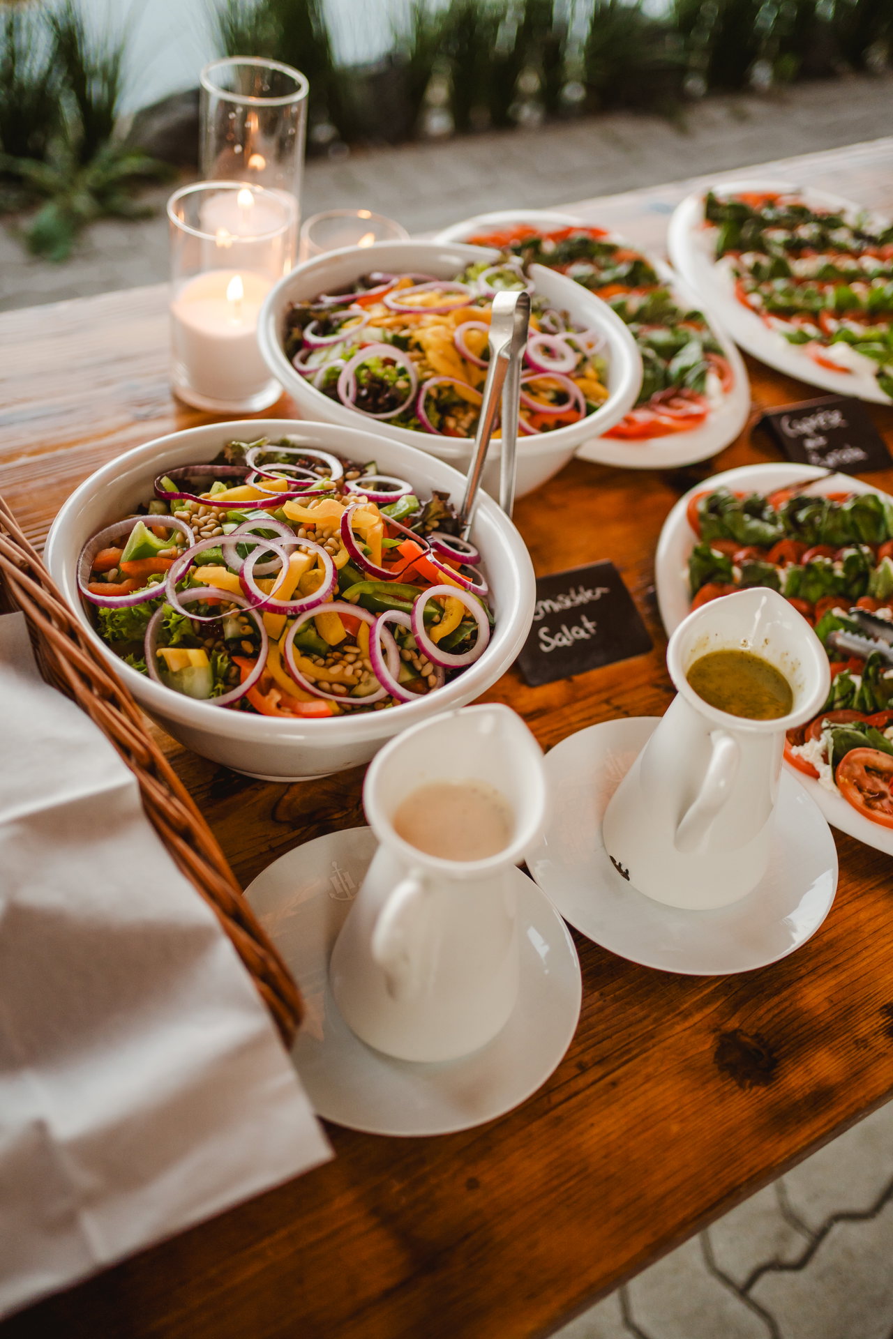 Schüsseln mit Salat und Dressing in Porzellankännchen