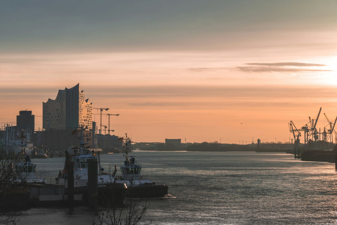 Sonnenaufgang über der Elbe, links die Elbphilharmonie, rechts Hafenkräne