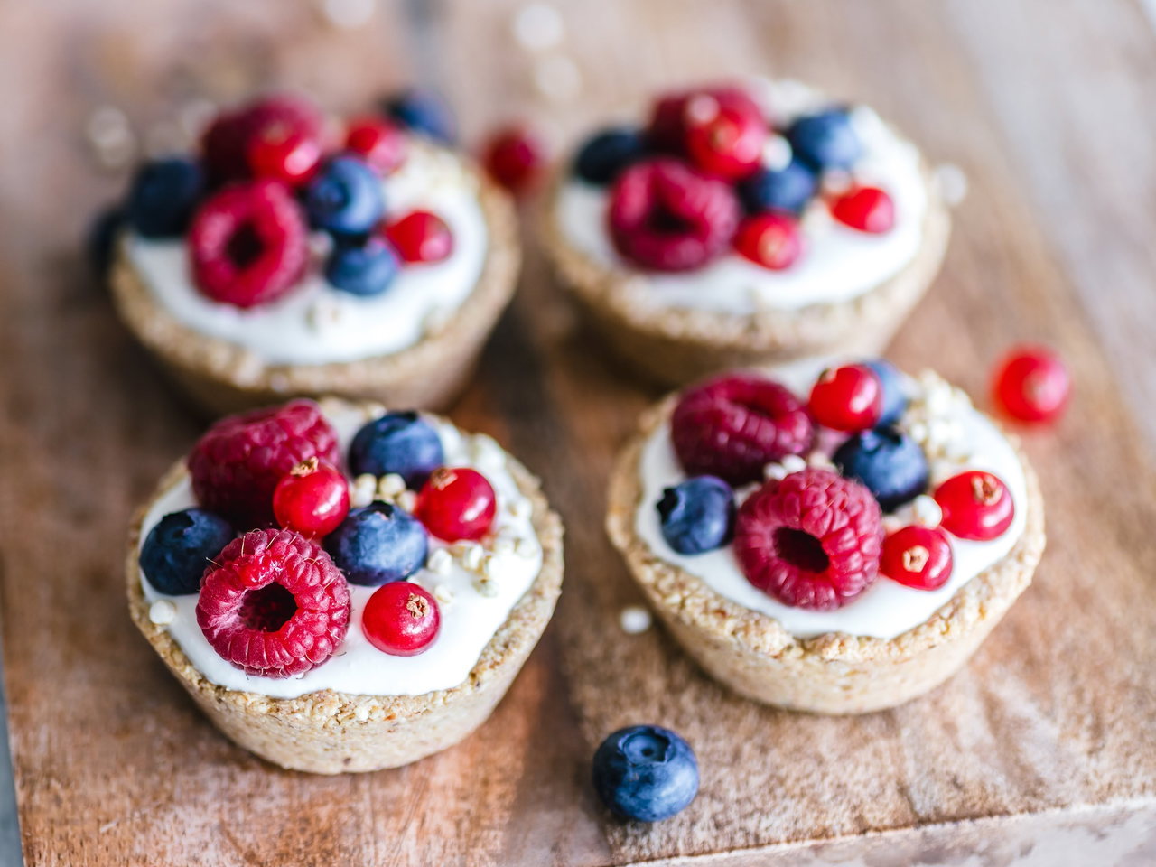 Kleine Törtchen mit Creme, Himbeeren, Blaubeeren und Johannisbeeren