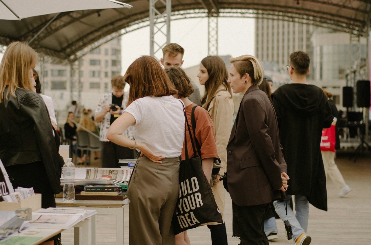 Besucherinnen und Besucher schlendern in einer Messehalle an Ausstellungsständen mit Broschüren und Infomaterial vorbei