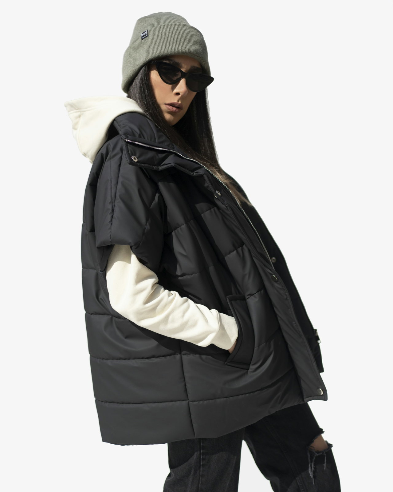 Oversize-Steppweste in Schwarz mit hellen Ärmeln, studiohell fotografiert