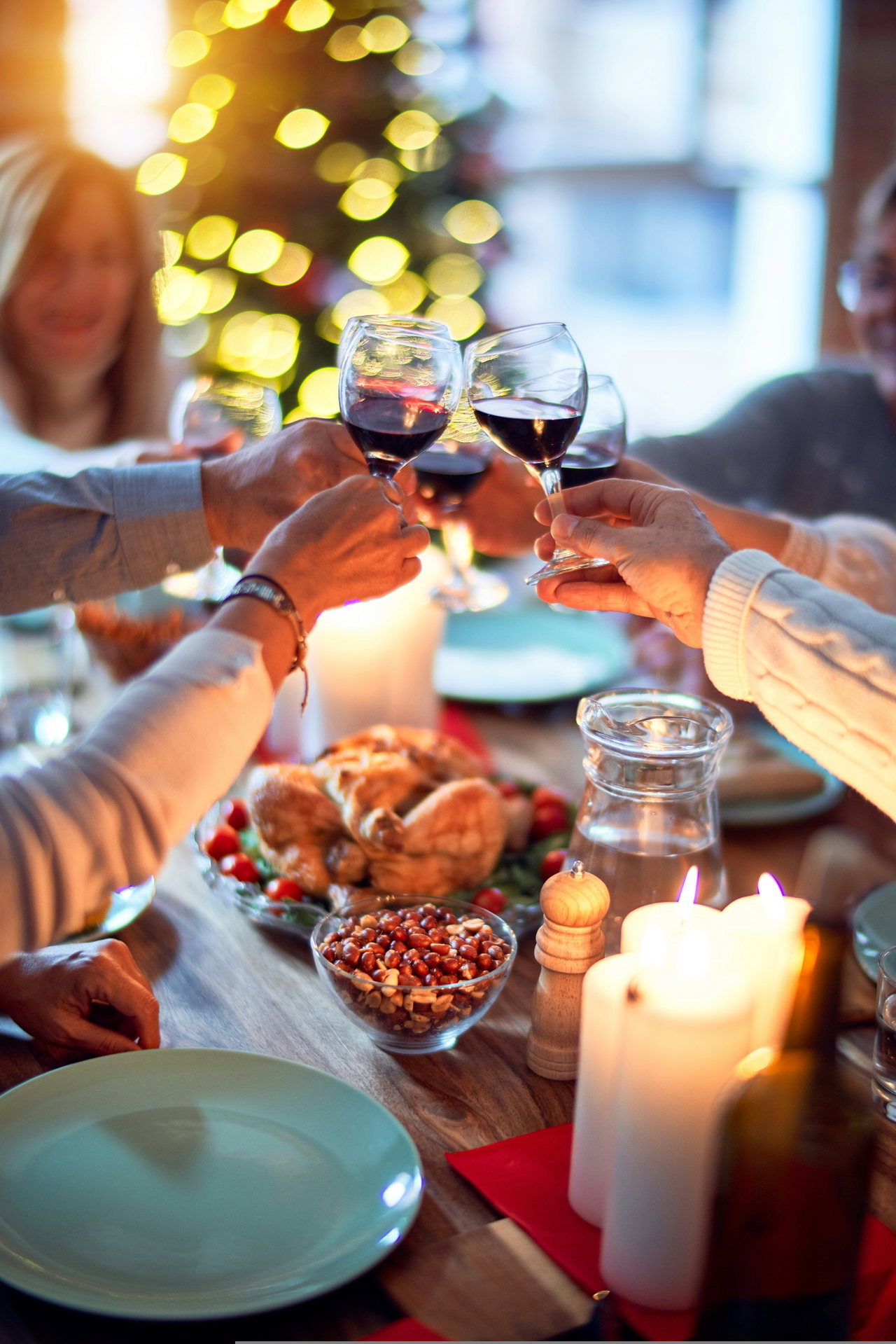 Kolleginnen und Kollegen stoßen am festlich gedeckten Tisch mit Rotwein an