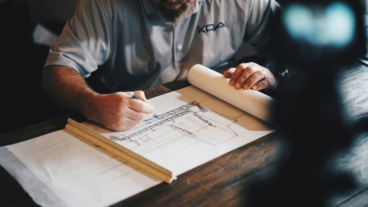 Ein Architekt zeichnet mit Stift und Lineal an einem Bauplan