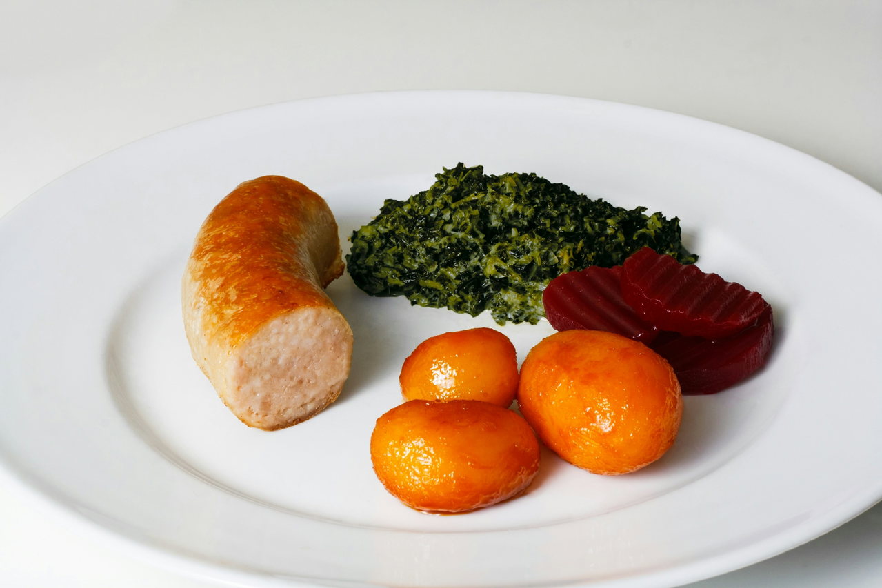 Teller mit Kochwurst, gedünstetem Grünkohl, karamellisierten Kartoffeln und Rote-Bete-Scheiben