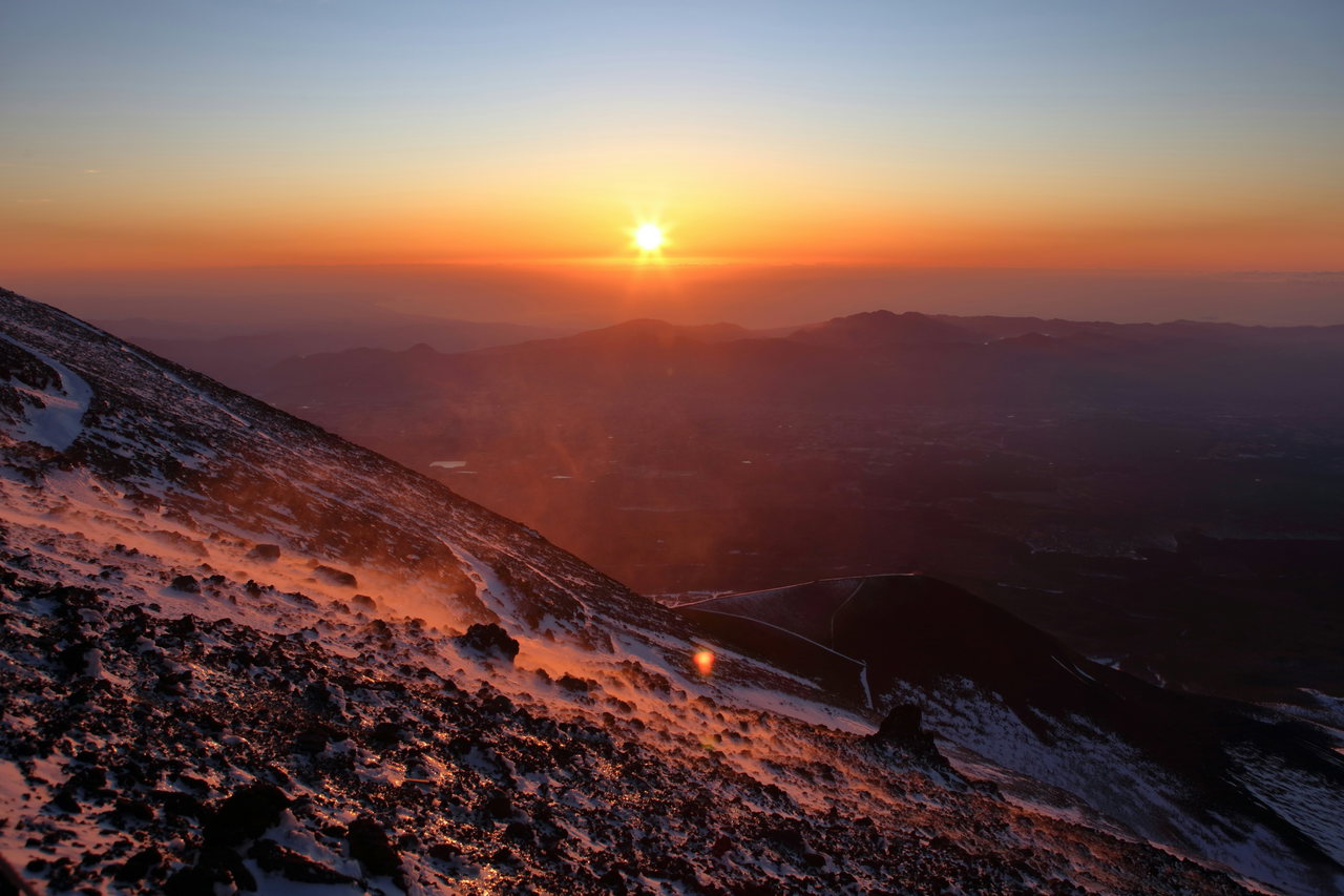 Sonnenaufgang über einem Wolkenmeer, im Vordergrund der Vulkanhang mit Schneeresten