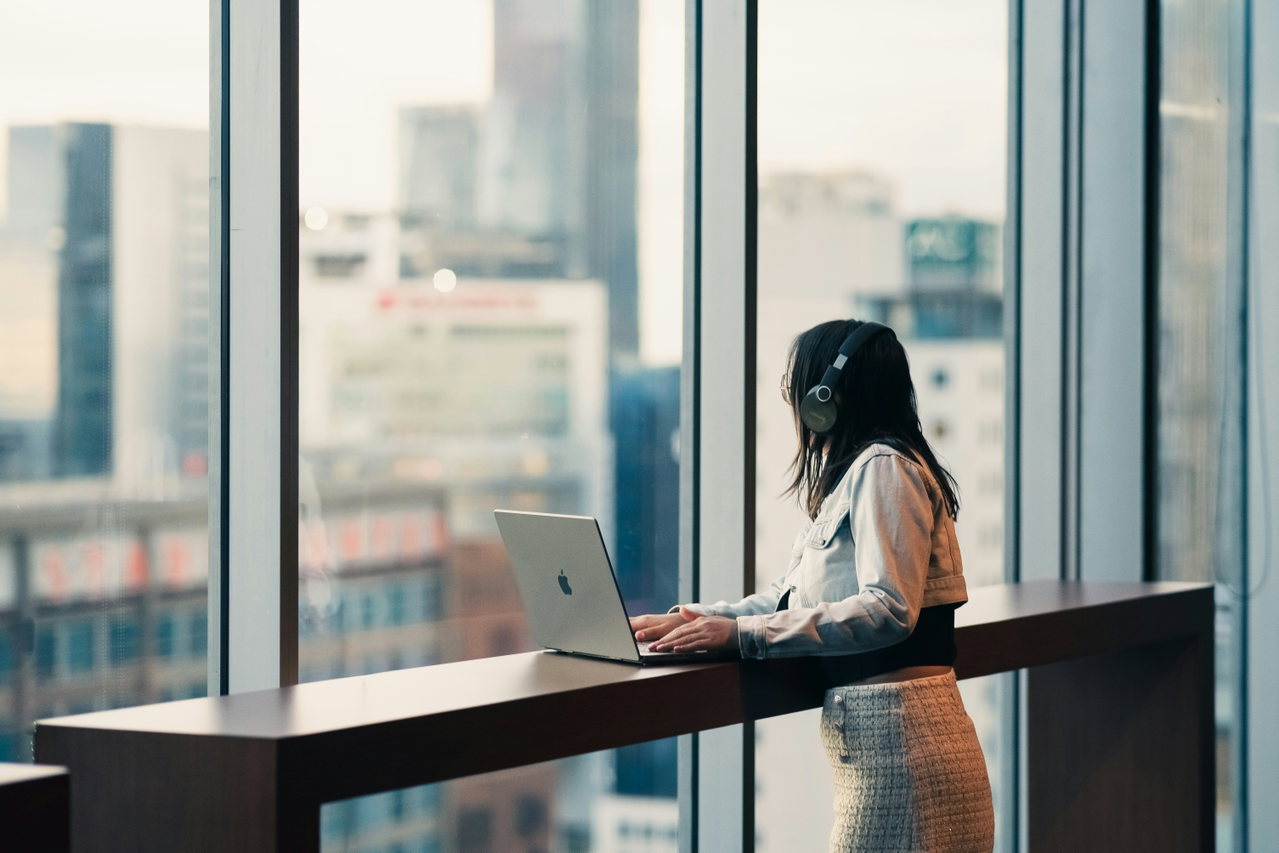 Frau arbeitet am Laptop an einem hellen Fensterplatz im Büro