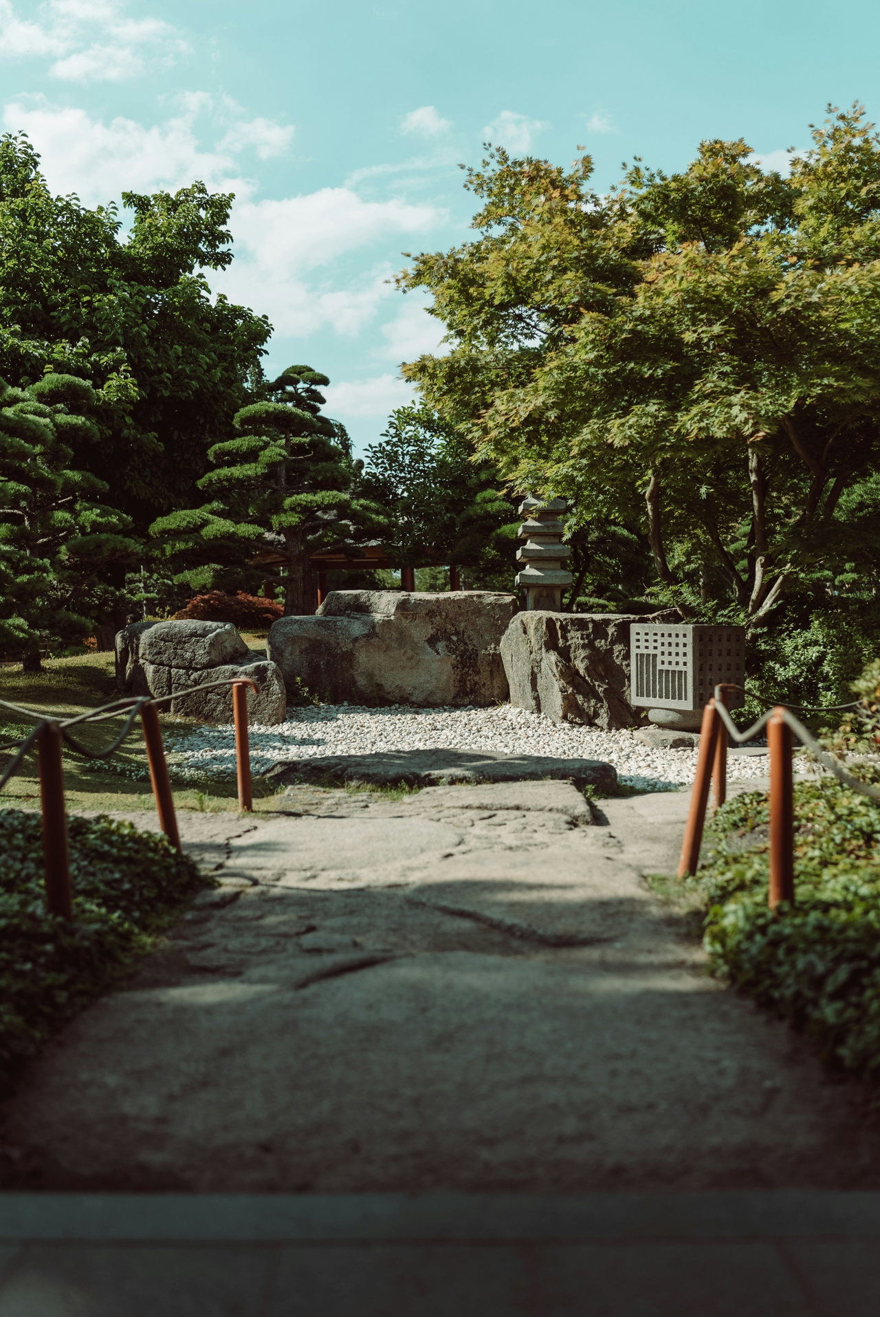 Steinweg mit Holzgeländer zwischen Kiefern im Japanischen Garten