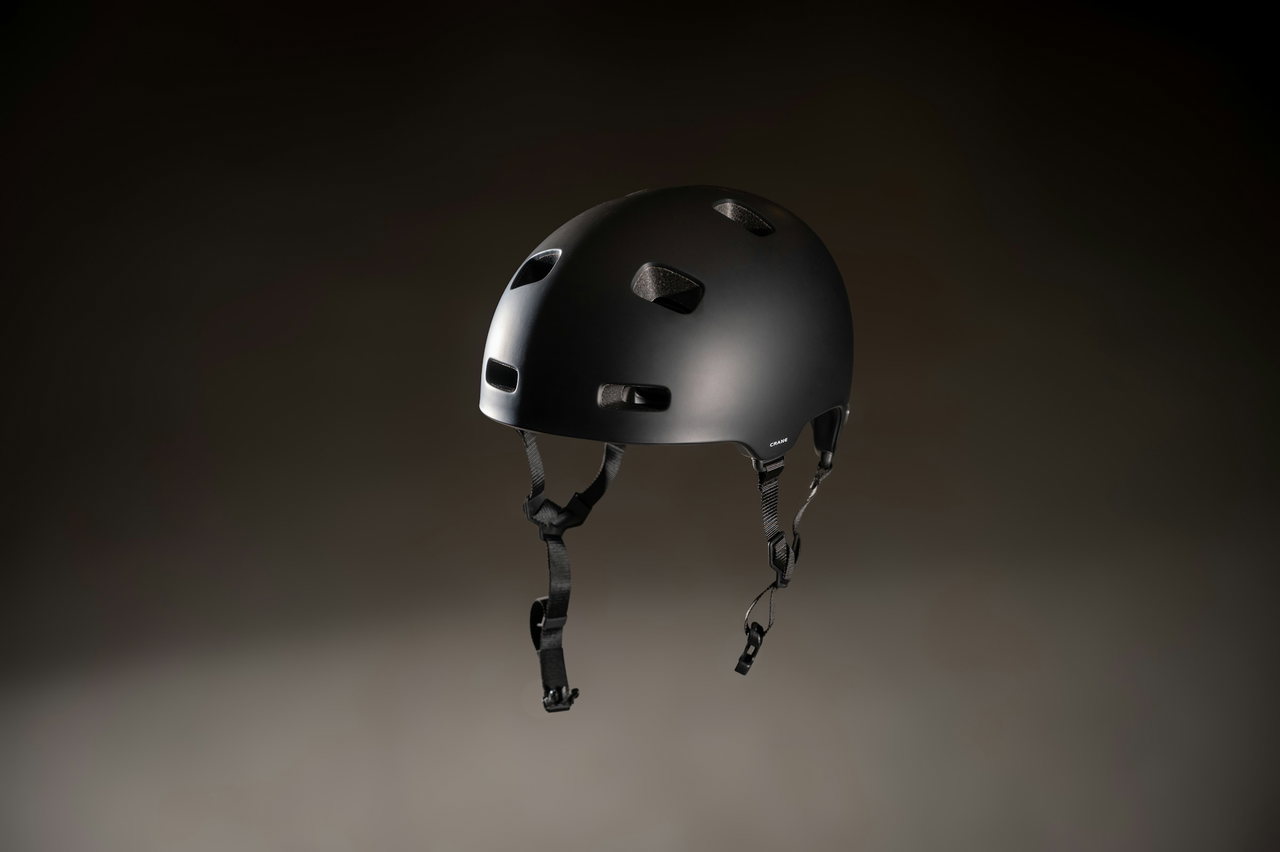 Schwarzer Fahrradhelm mit Lüftungsöffnungen schwebt vor dunklem, sanft ausgeleuchtetem Studiohintergrund