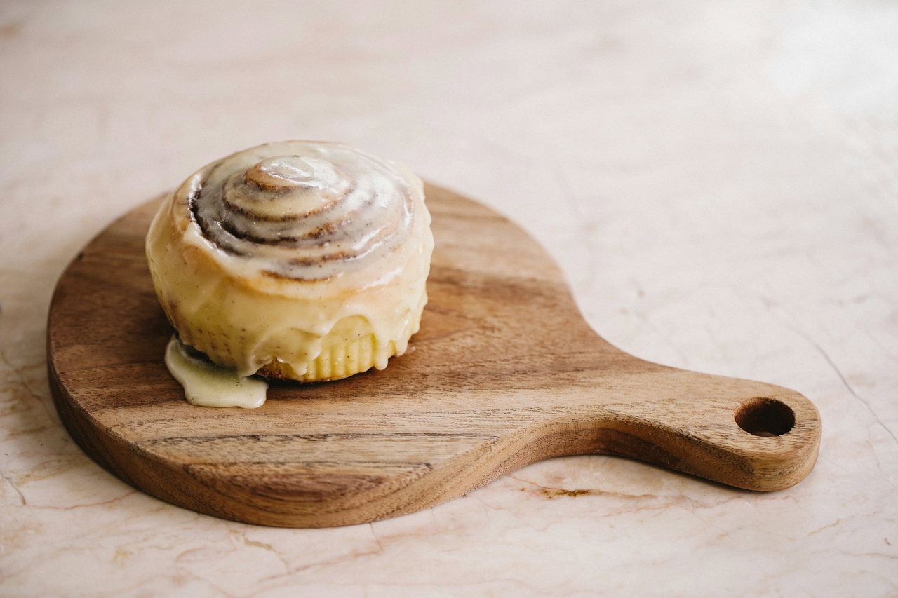 Zimtschnecke mit Zuckerguss auf einem Holzbrett dekoriert