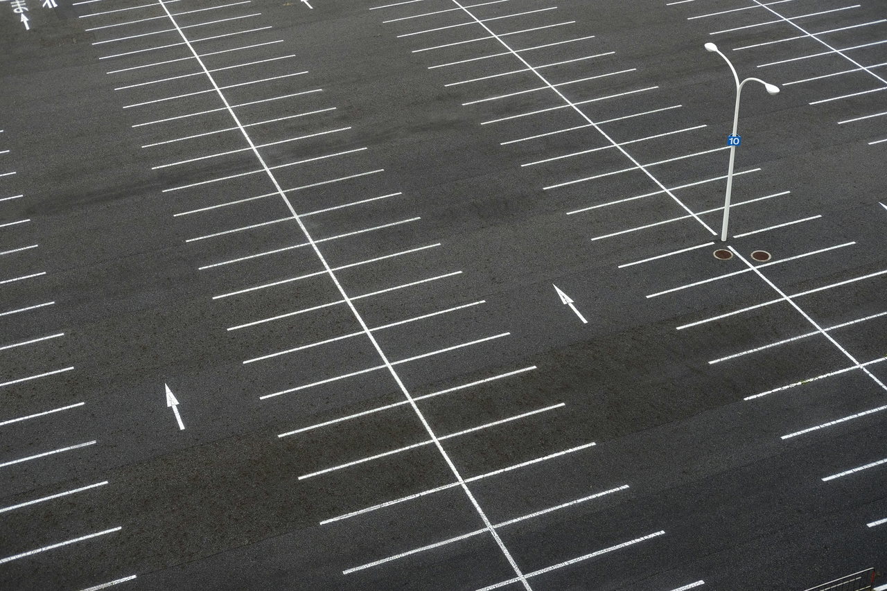 Leerer Parkplatz mit weißen Markierungen auf grauem Asphalt