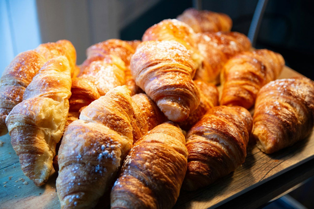 Goldbraune Croissants liegen dicht an dicht auf einem Holzbrett im warmen Licht