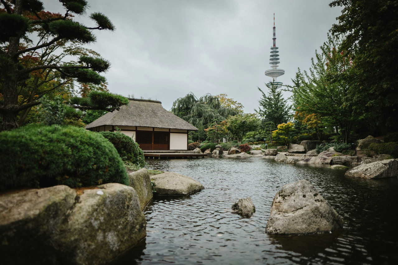 Japanischer Garten mit Teehaus, Steinen und Teich, dahinter der Fernsehturm