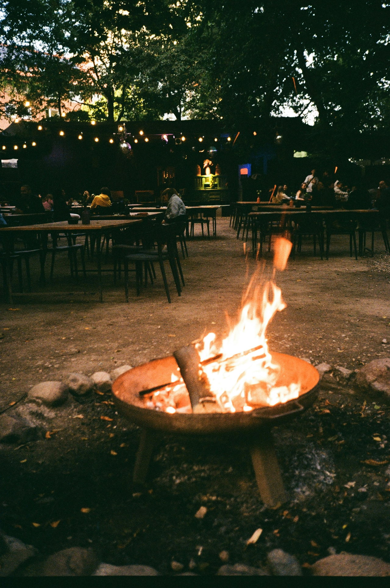Brennender Feuerkorb in einem Biergarten mit Lichterketten