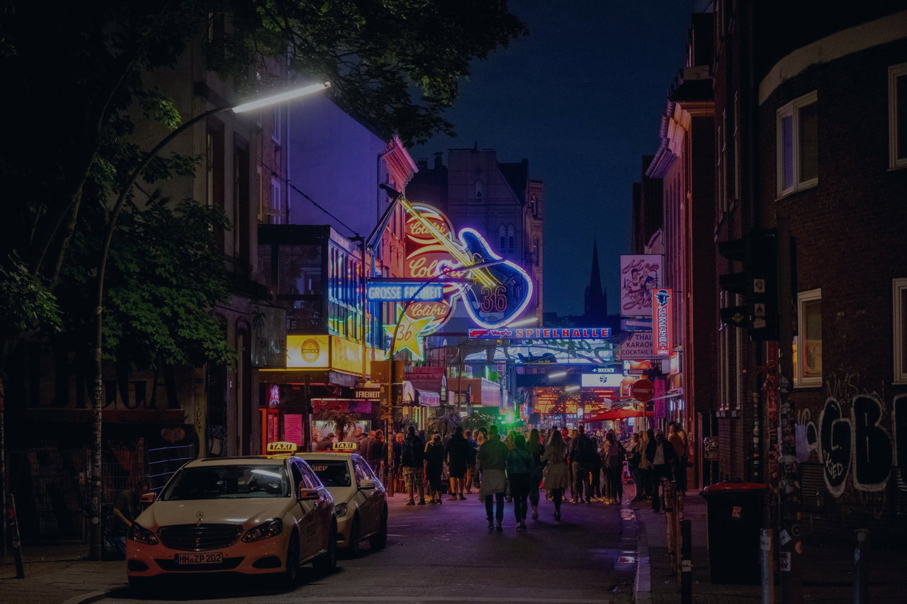Die Reeperbahn bei Nacht mit Leuchtreklamen und Taxis