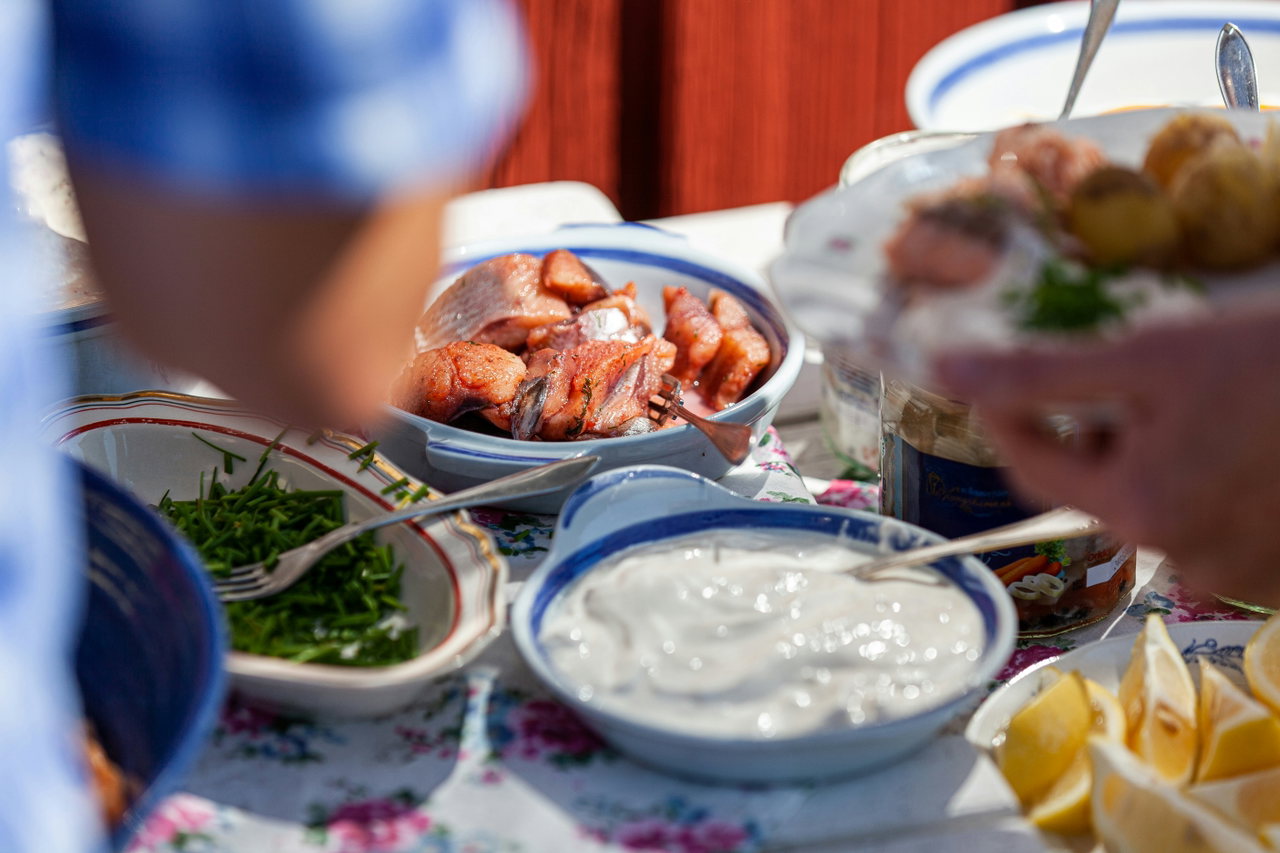 Gedeckter Tisch mit Hering, Kräutern, Schmand und Zitronen