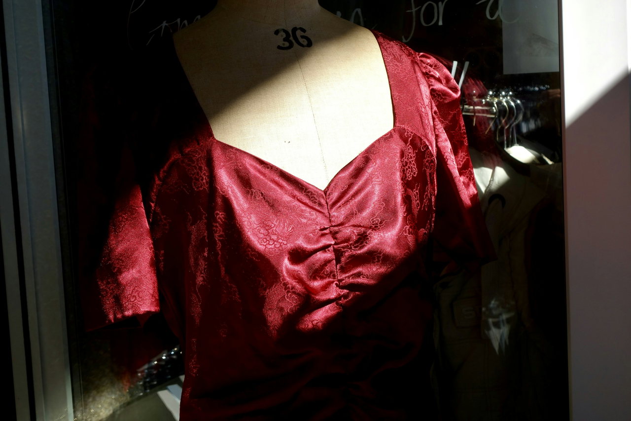 Satinkleid in tiefem Rot auf einer Schneiderbüste im Seitenlicht