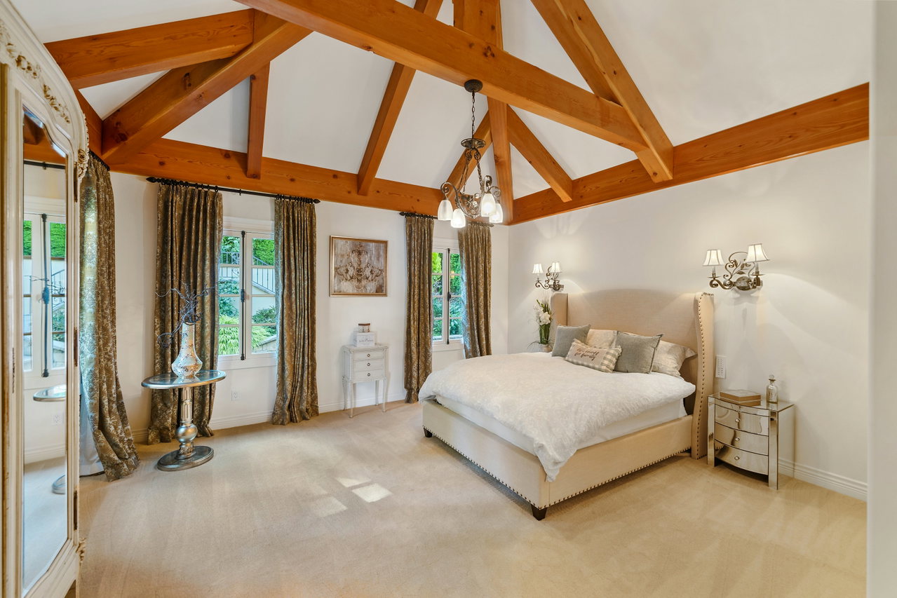 Großzügige Suite mit sichtbaren Holzbalken im Dach, breitem Bett und hohen Fenstern