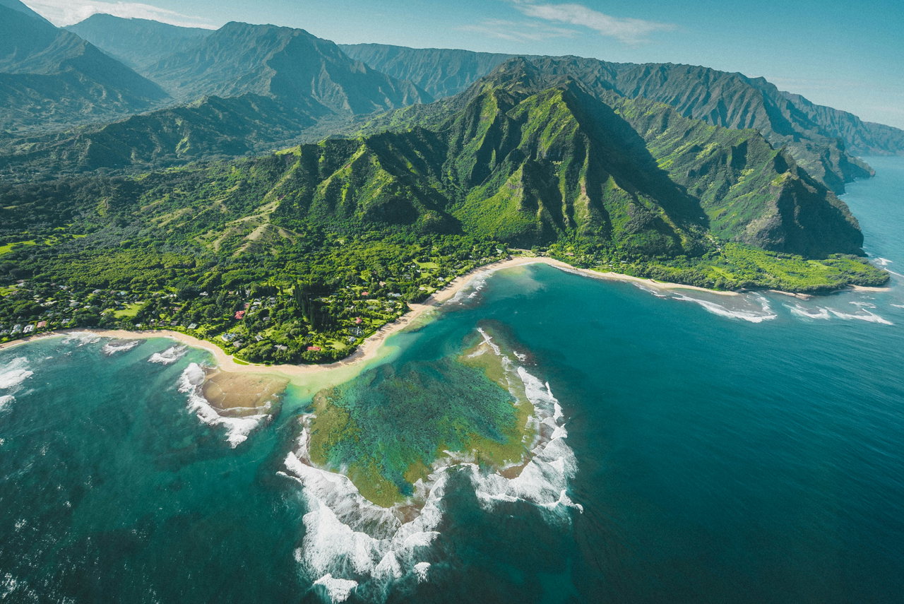 Grüne Berge und Riff an der Küste Hawaiis aus der Luft
