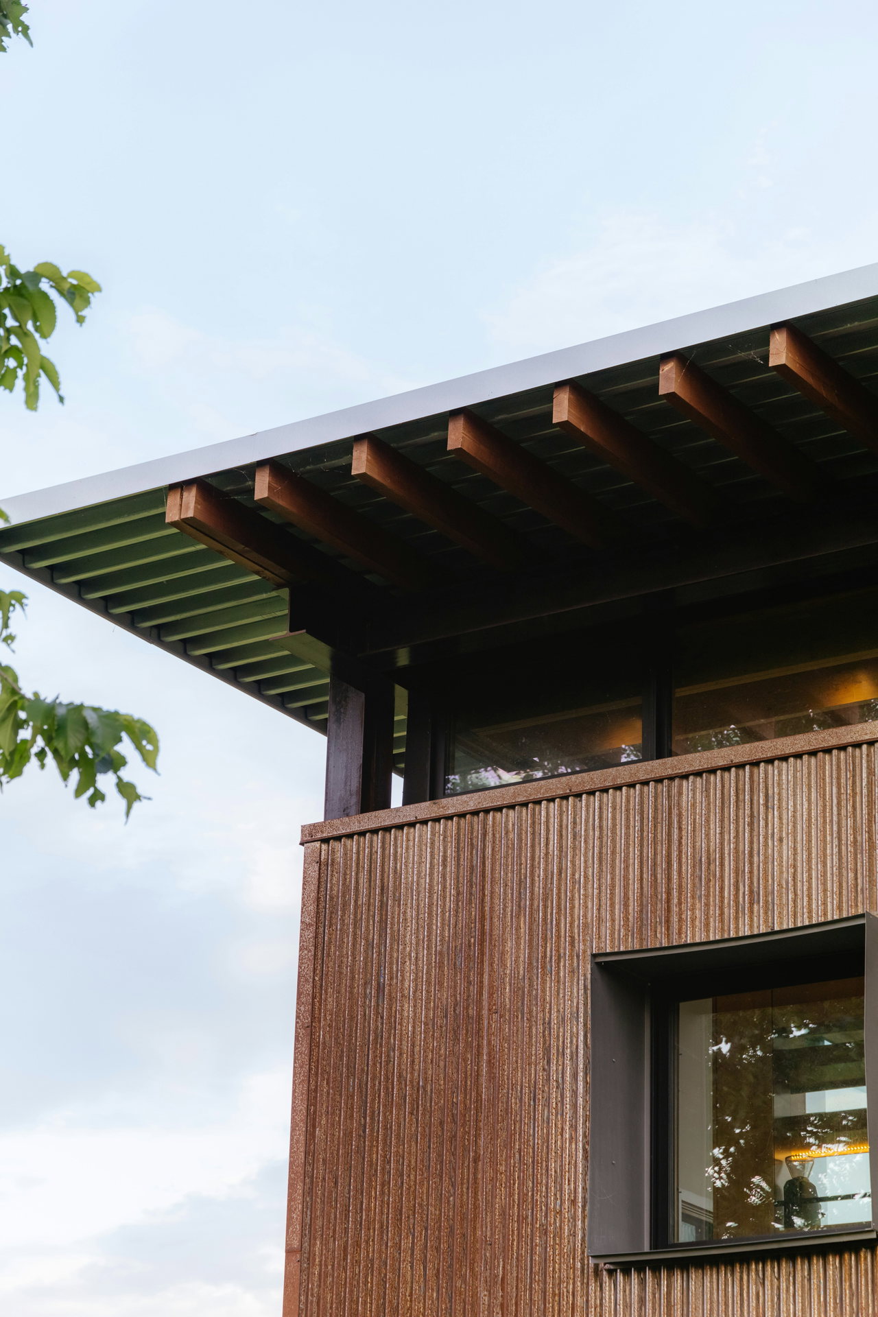 Moderner Holzbau mit dunkler Lattenfassade und weitem Dachüberstand