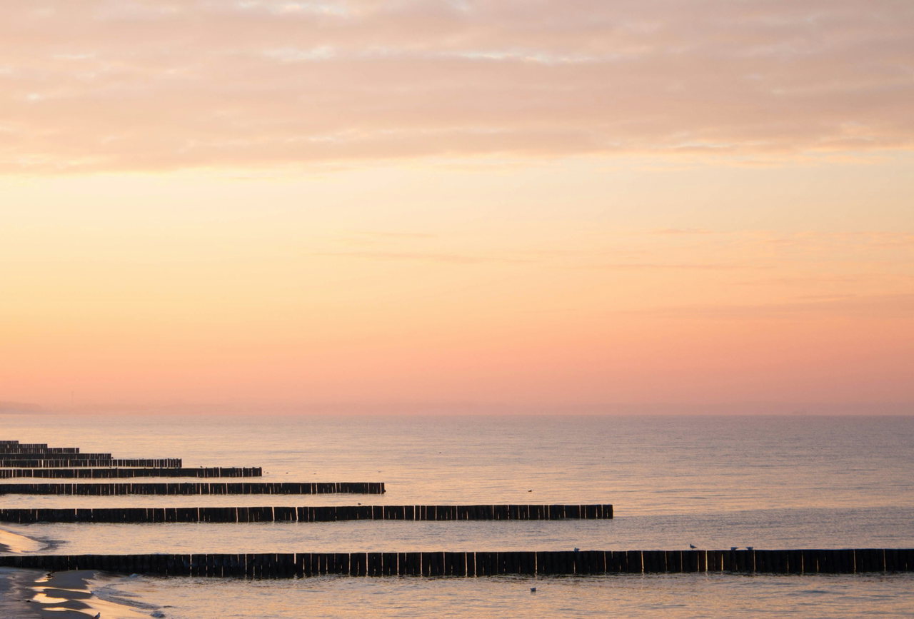 Buhnen im ruhigen Meer bei Sonnenuntergang