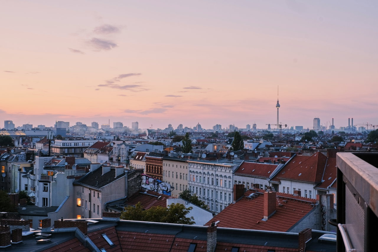 Altbaudächer und Hinterhöfe unter einem rosa-blauen Morgenhimmel, der Fernsehturm am Horizont