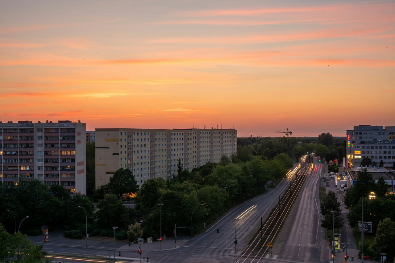 Plattenbauten und eine leere Straße im ersten Morgenlicht, Himmel orange