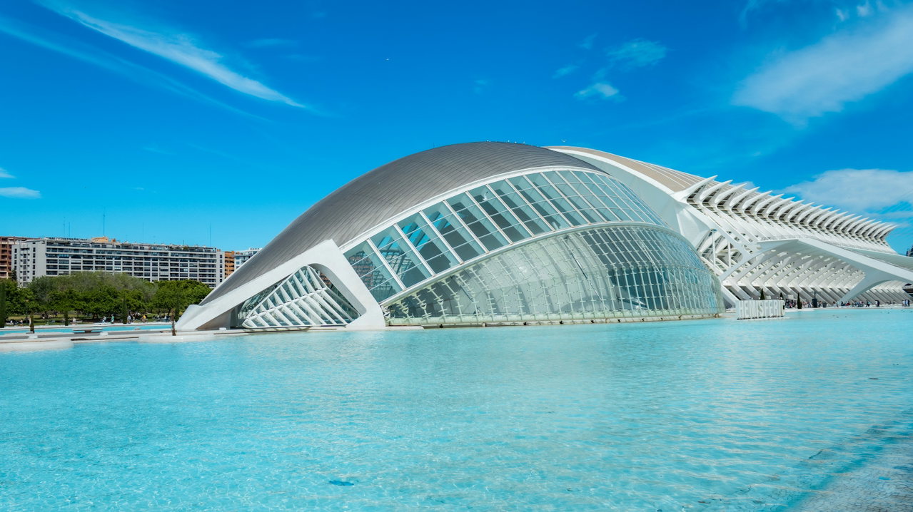 Futuristisches Gebäude der Stadt der Künste und Wissenschaften in Valencia hinter türkisfarbenem Wasserbecken