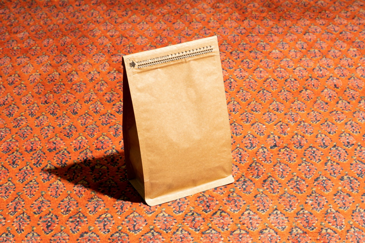 Kaffeetüte aus Kraftpapier auf gemustertem Grund