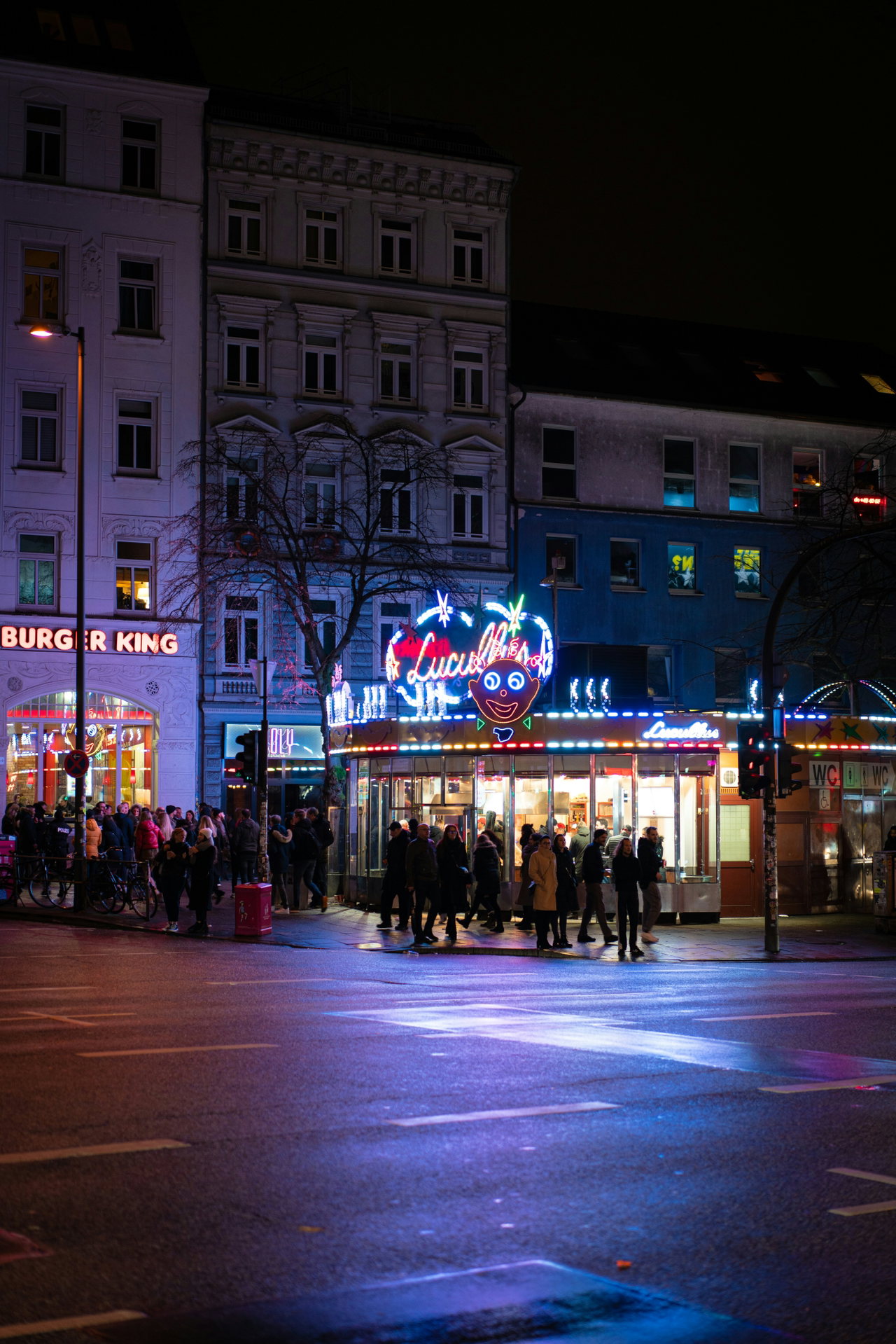 Beleuchtete Imbisse und Menschen an einer Kreuzung auf St. Pauli bei Nacht