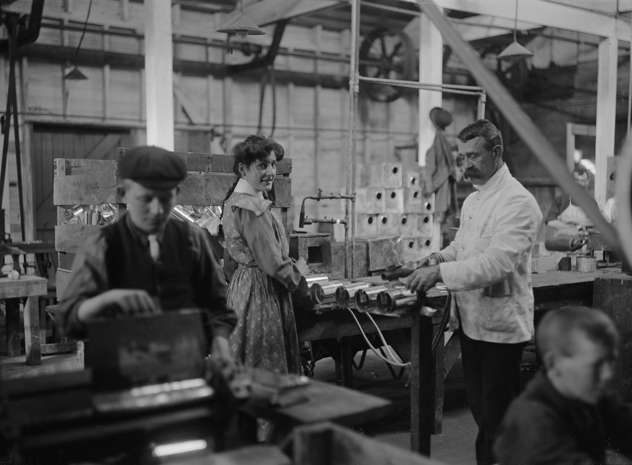 Historisches Schwarz-Weiß-Foto: Arbeiter an Maschinen in einer Werkhalle