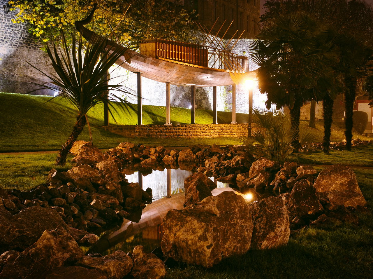 Ein beleuchteter Garten mit Teich bei Nacht