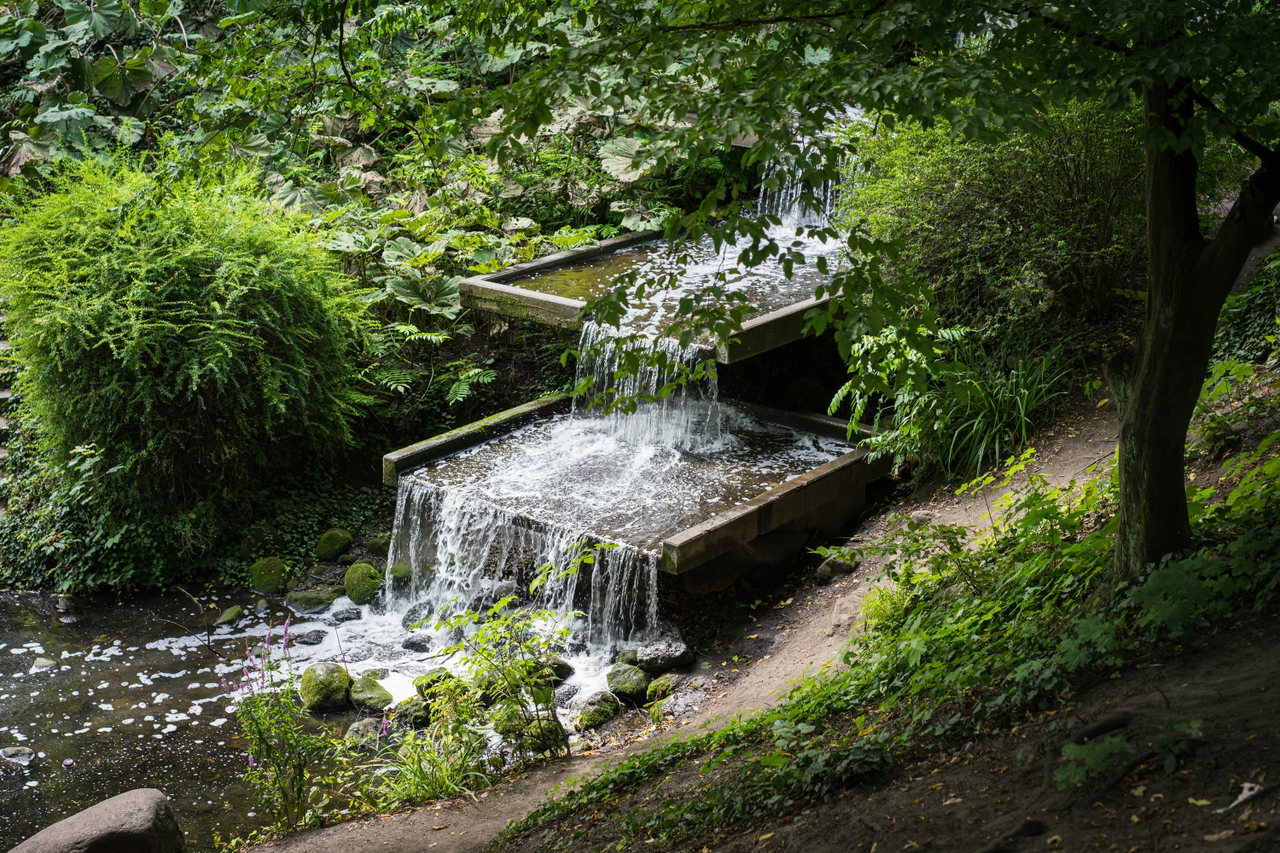 Kleiner Wasserfall zwischen Felsen und üppigem Grün