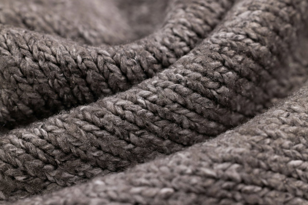 Nahaufnahme eines grobmaschigen Strickstoffs in Braungrau mit weichen Falten
