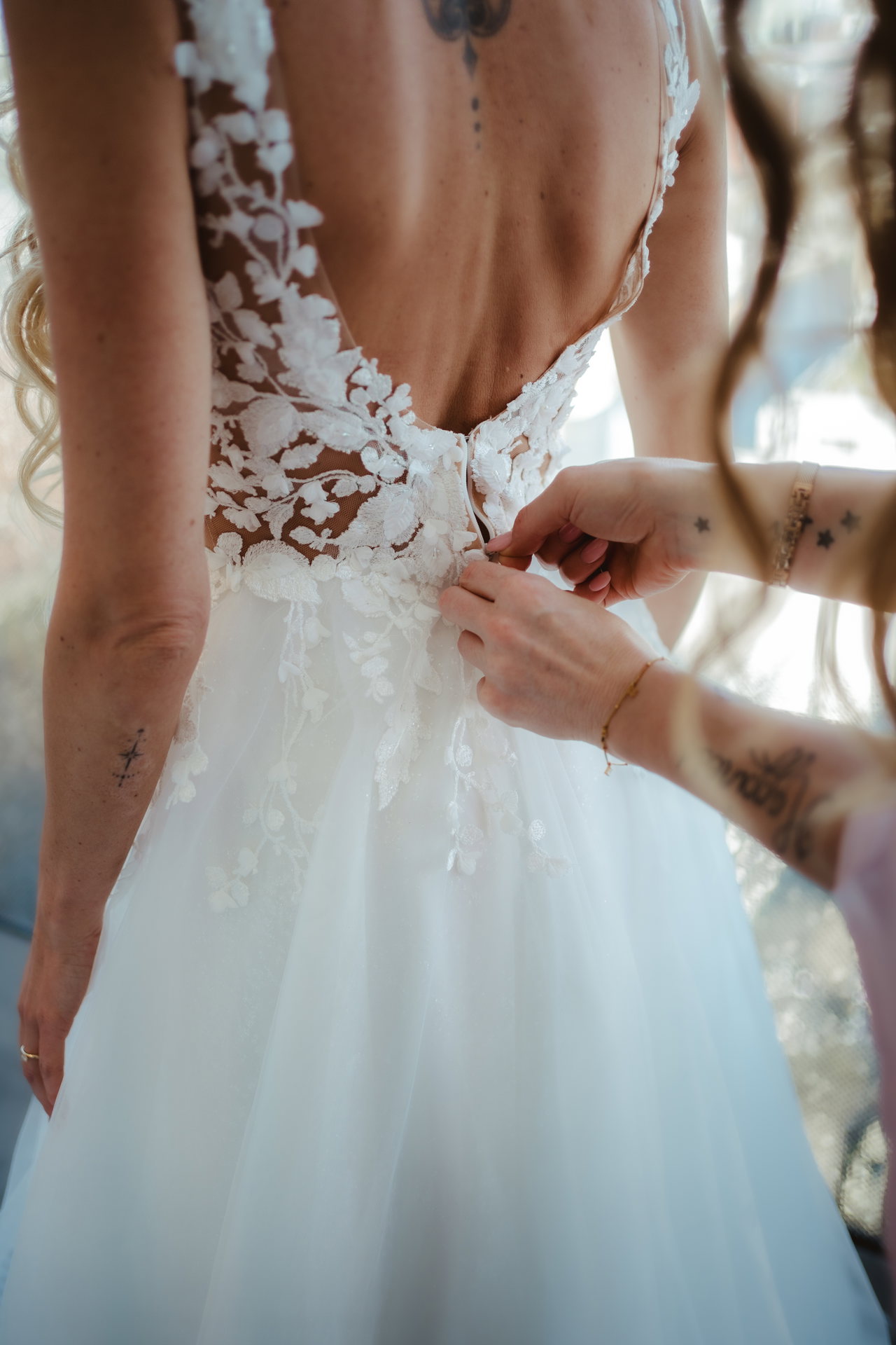 Hände schließen das Spitzenkleid am Rücken