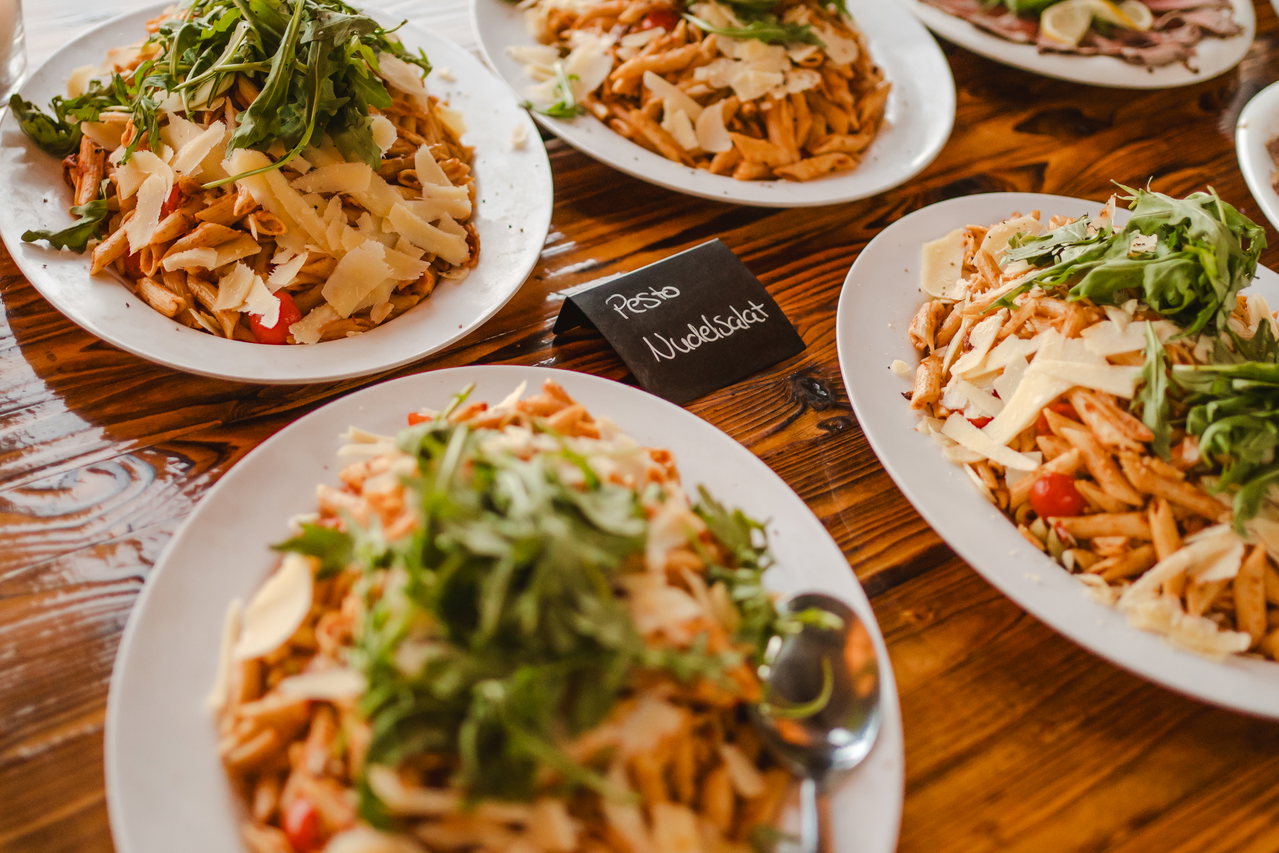 Teller mit Pasta und Rucola auf einem Holztisch, daneben ein Kreideschild